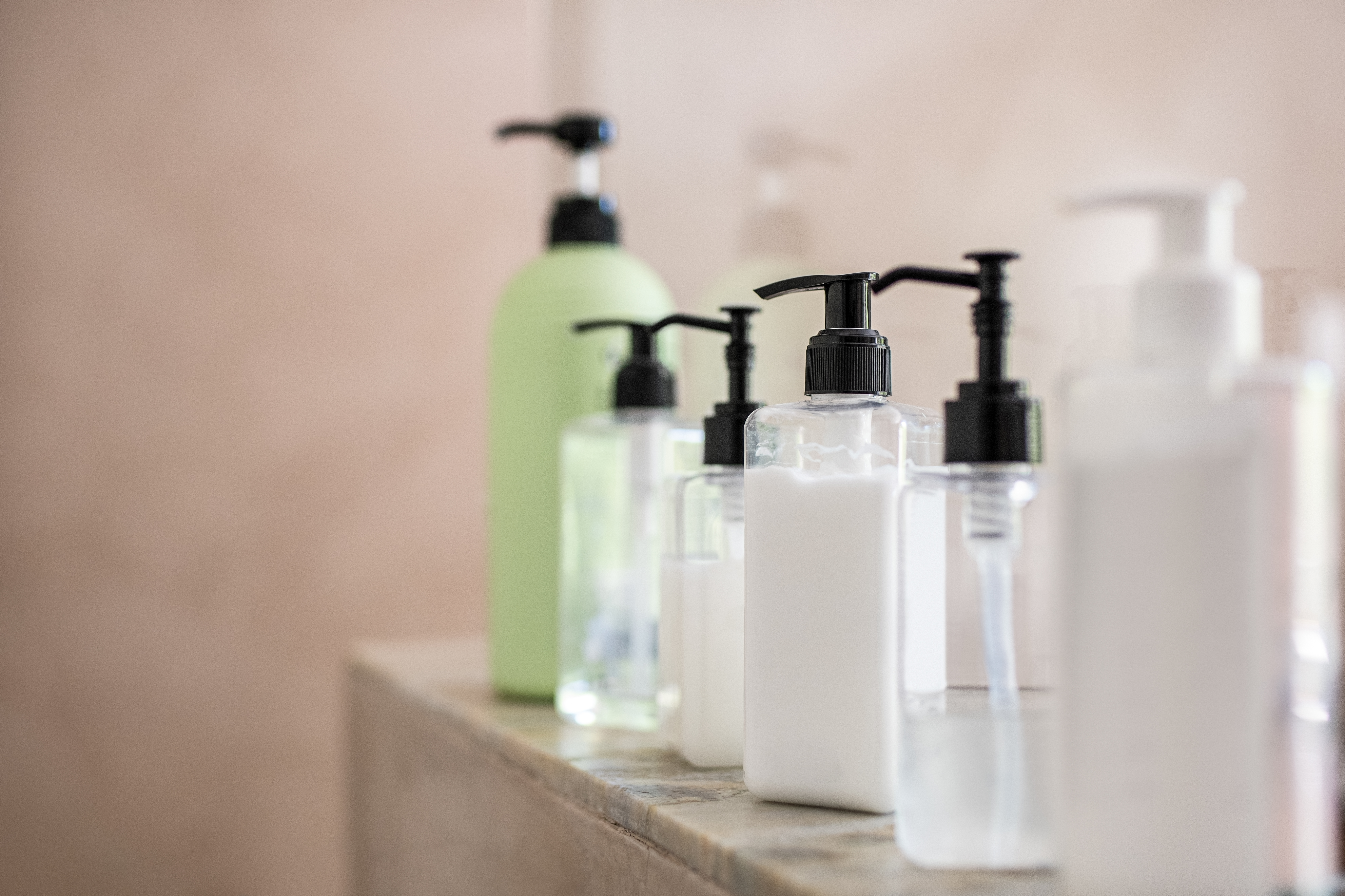 Shampoo bottles lined up on a shelf in a shower