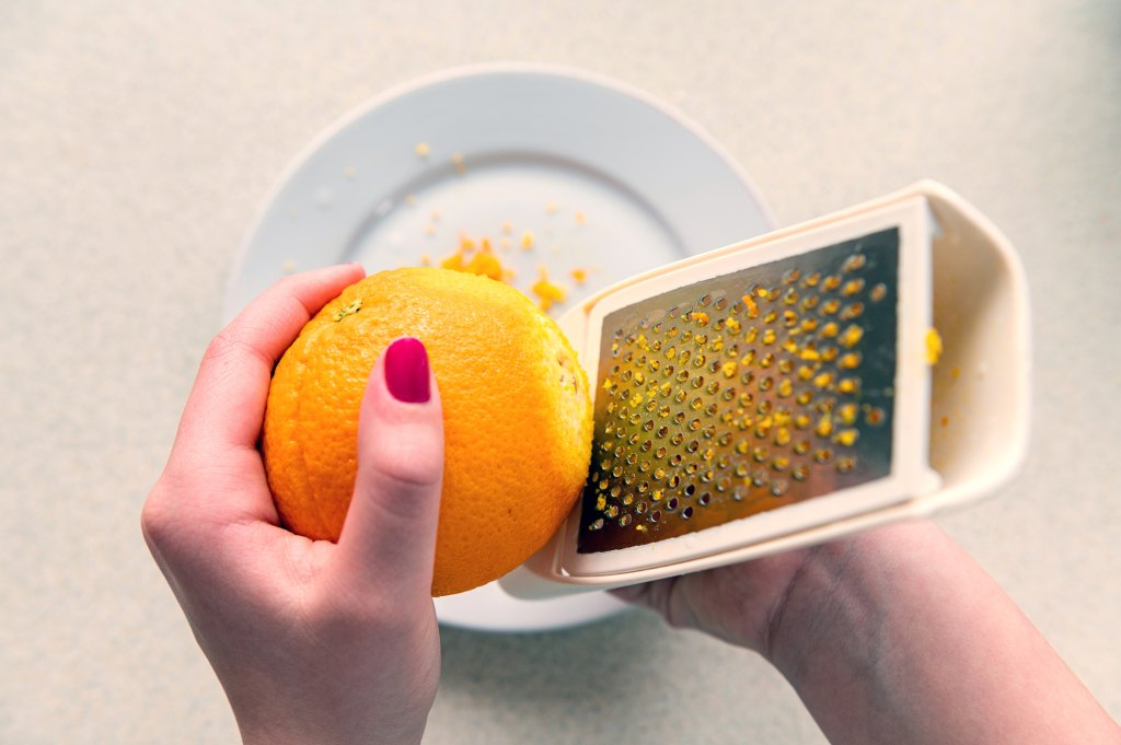 Zesting an orange using a metal grater,
