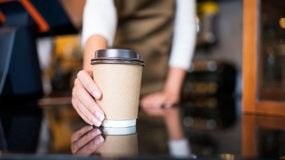 A coffee cup being handed over by a barista and contains a low calorie option