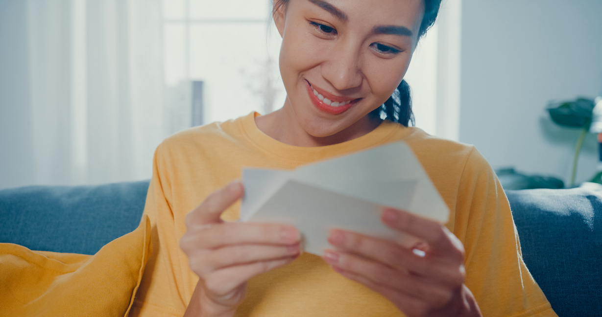 Happy Asian woman looking at a note card