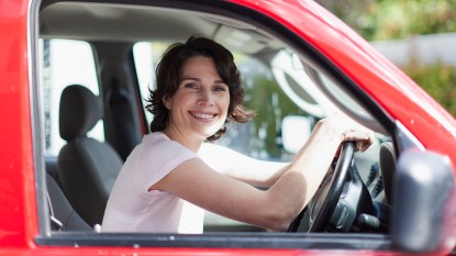 Woman sitting a red car making money while using a driving app