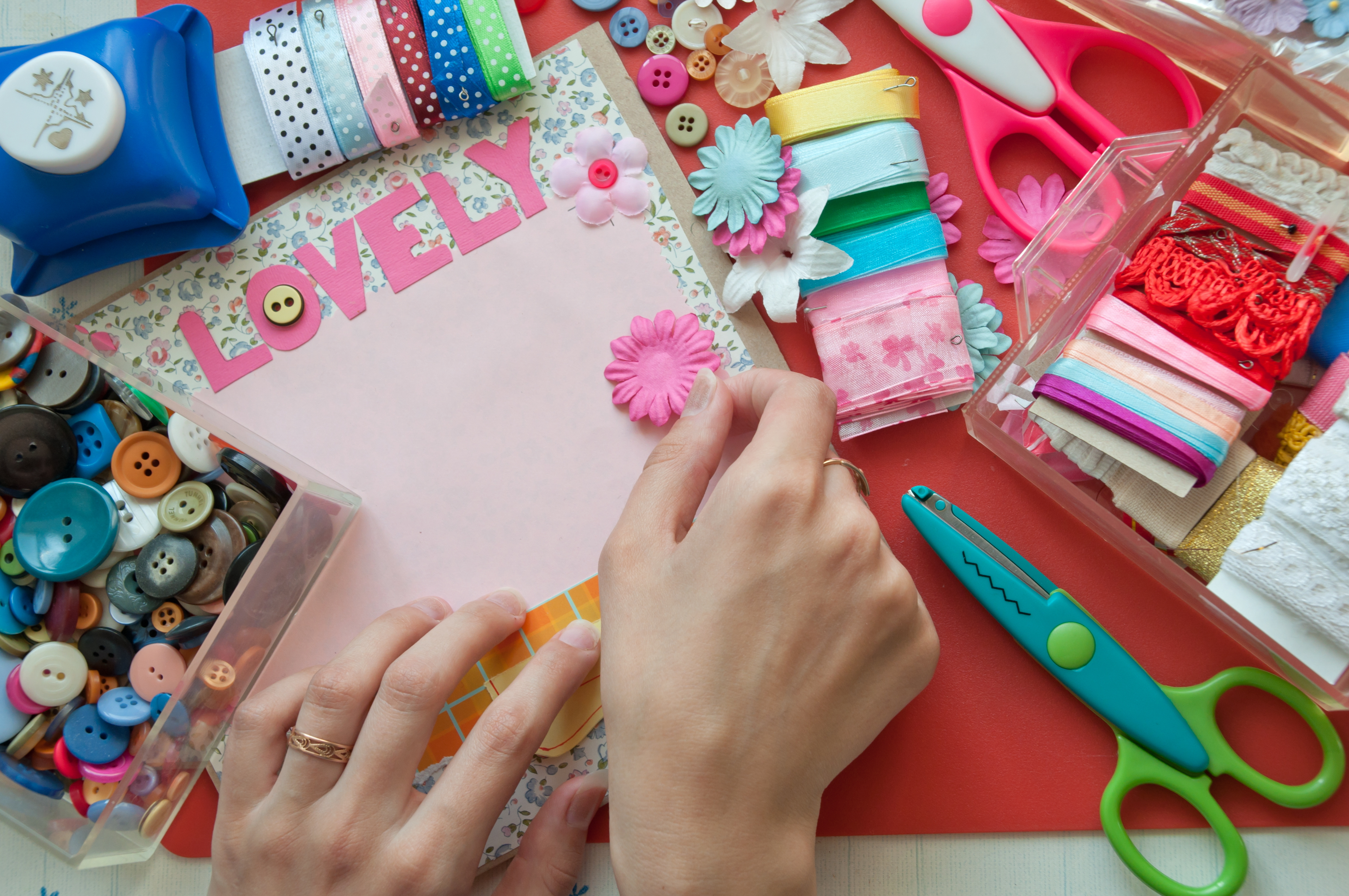 A woman's hands working with various colorful crafting supplies 
