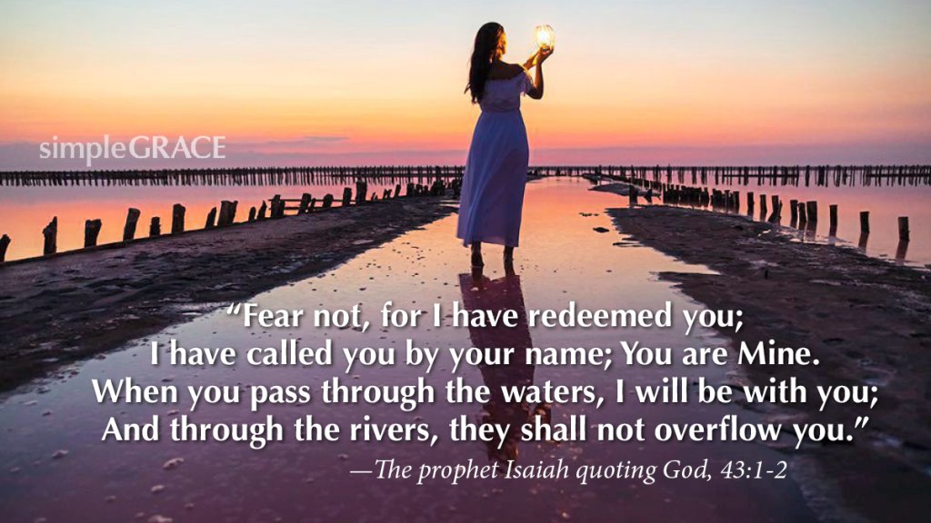 A woman standing with a lamp in her hand in still water at sunset