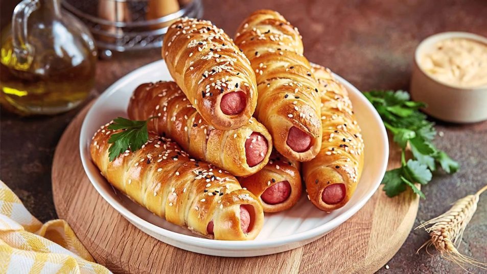 Pigs in a Blanket sits on a wooden cutting board (air fryer appetizers)