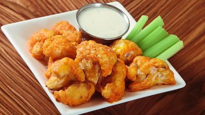 Buffalo Cauliflower Bites sits on a wooden table (air fryer appetizers)