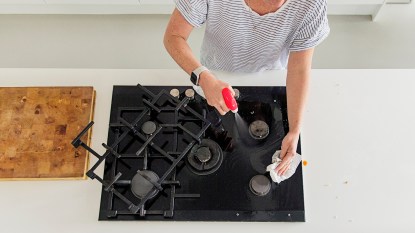 Overhead view of a woman cleaning stovetop