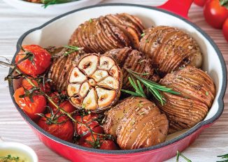 hasselback potatoes recipe: potatoes in dish with tomatoes and garlic