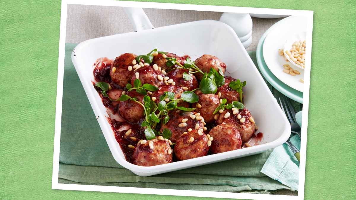 Cranberry-Glazed Meatballs sits in a white bowl (Game day slow cooker recipes)