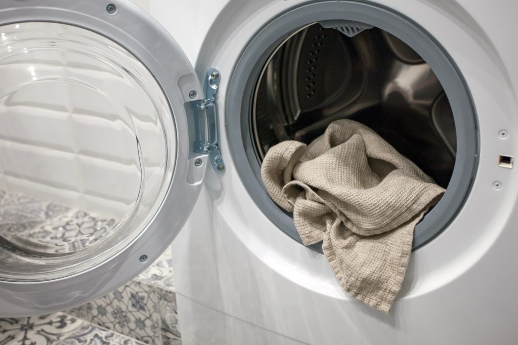 Towel hanging out of a washing machine (get rid of washing machine smell )