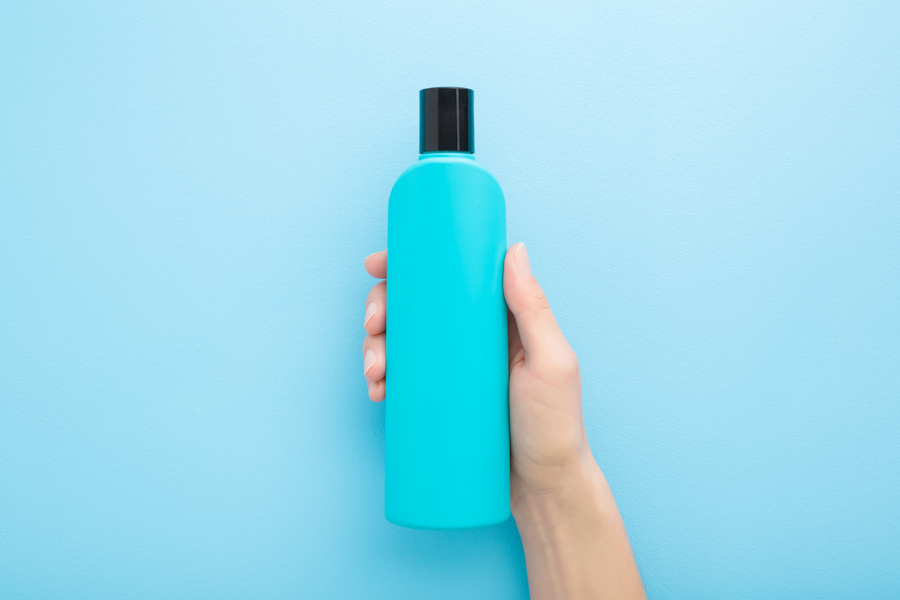 woman hand holding up blue shampoo