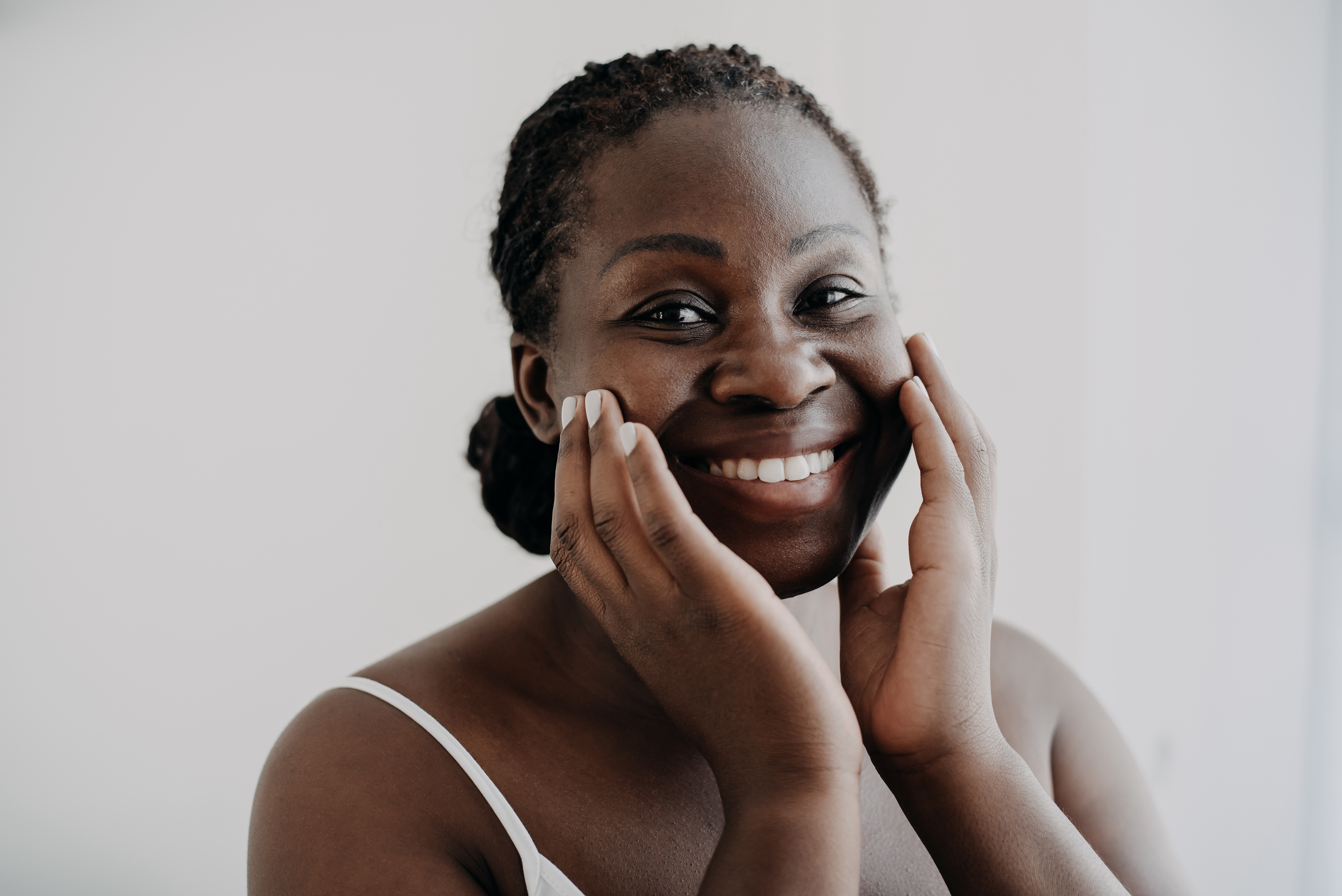 A mature Black woman getting face massage benefits by massaging her face