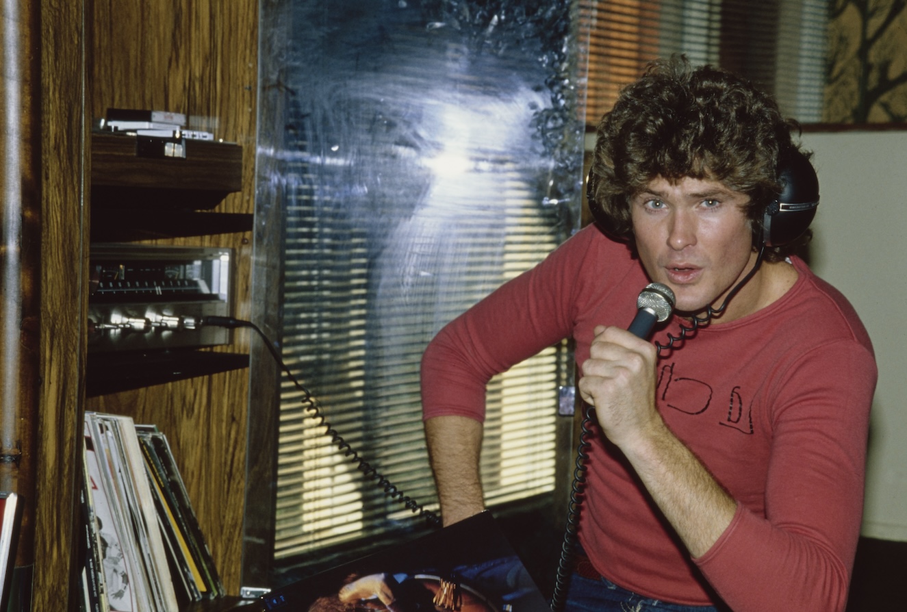 David Hasselhoff Movies and TV Shows: American actor and singer David Hasselhoff, wearing a red long-sleeve t-shirt as he holds a microphone which he sings into at his home in the Hollywood Hills neighbourhood of Los Angeles, California, November 1979.