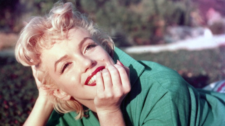 Marilyn Monroe smiling with chin in hand and her iconic makeup look on
