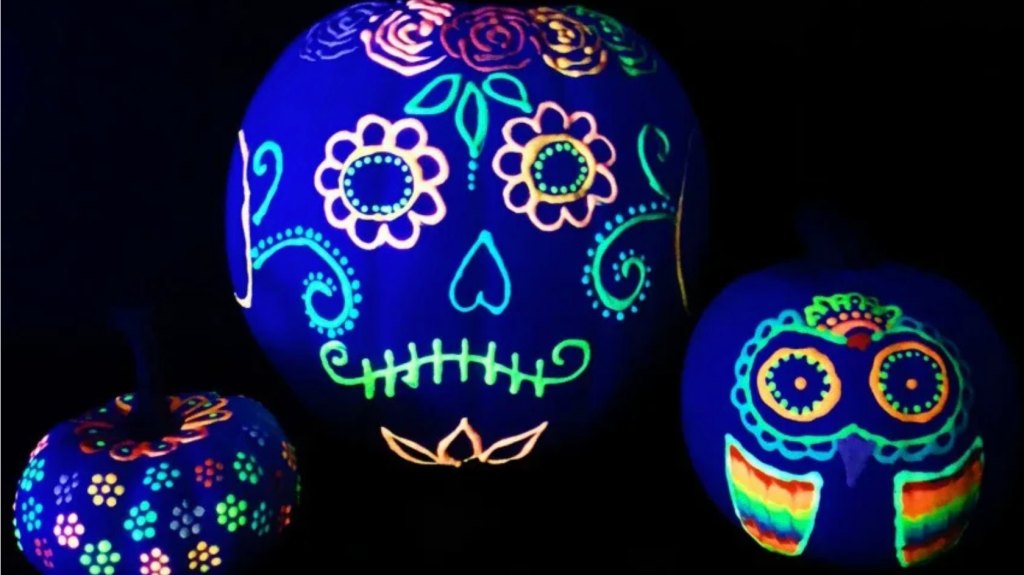 Pumpkin faces painted to look like sugar skulls using glow in the dark puffy paint