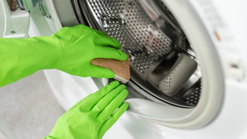 Gloved hands clean washing machine with open door (get rid of washing machine smell )