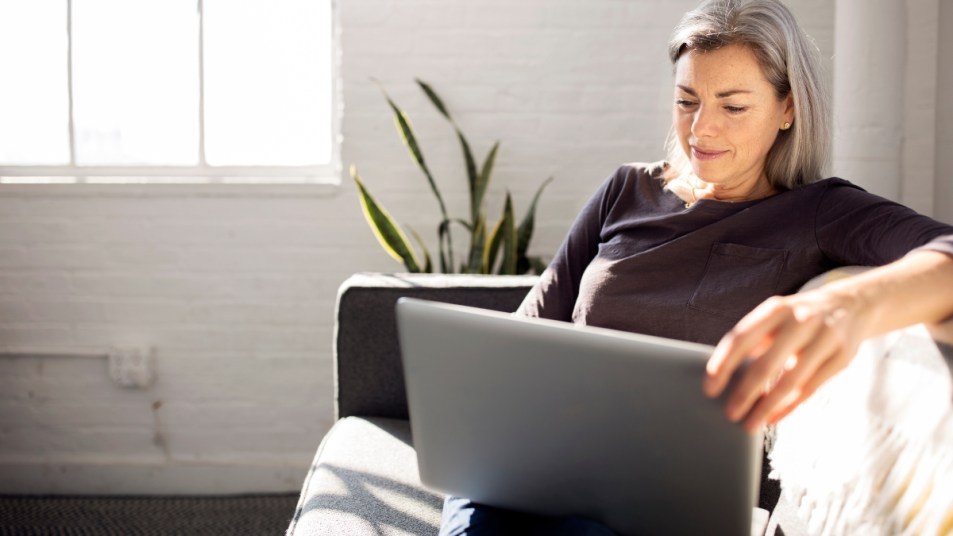 (CVS work from home)Woman using laptop while sitting on sofa in living room at home