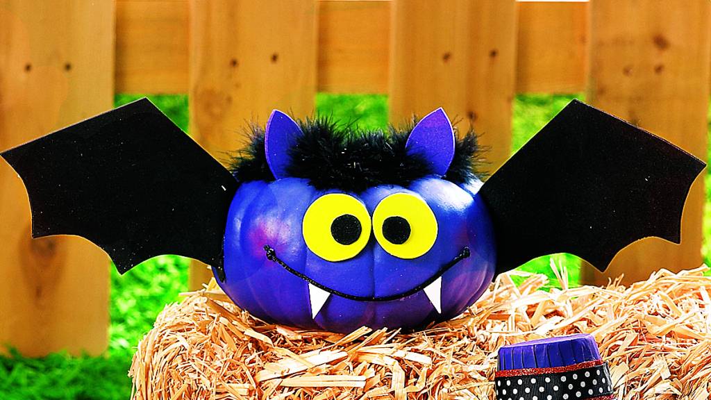 Pumpkin face painted and decorated to look like a bat with wings