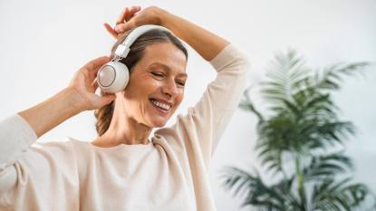 How to clean headphones: Happy businesswoman wearing wireless headphones dancing in office