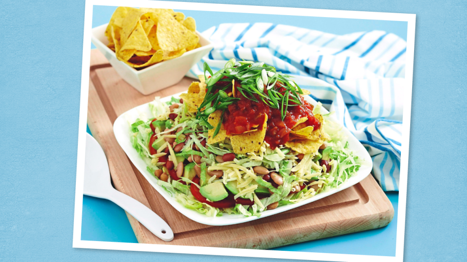 Stacked Taco Salad sits on a blue background (taco tuesday recipes)