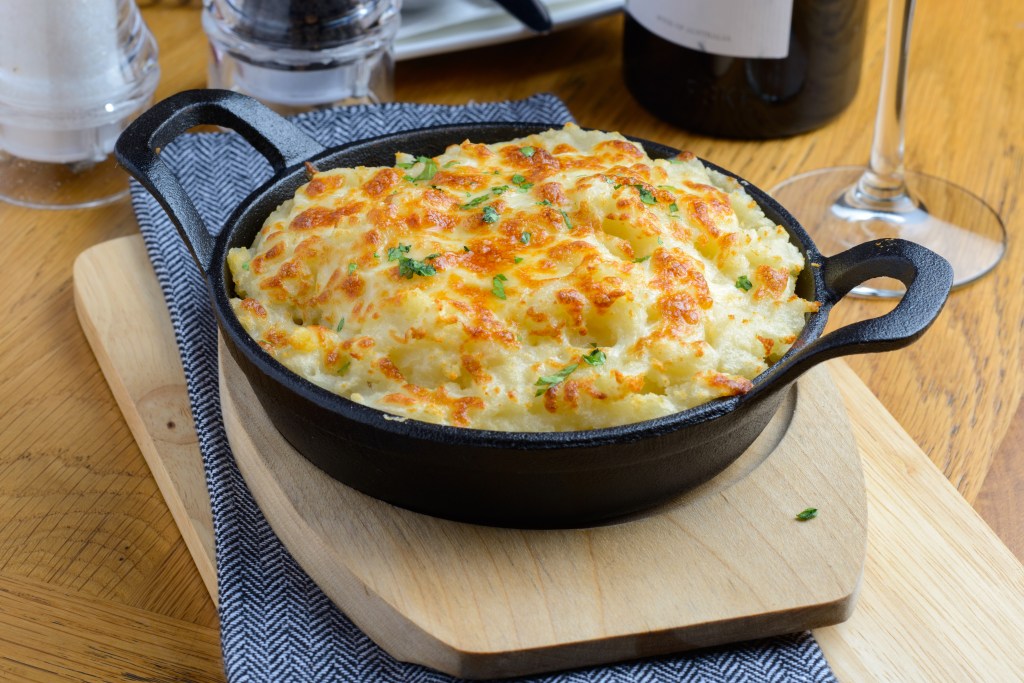 What to do with Thanksgiving leftovers: Shepherd's pie made with leftover mashed potatoes and turkey served on cutting board in cast iron skillet