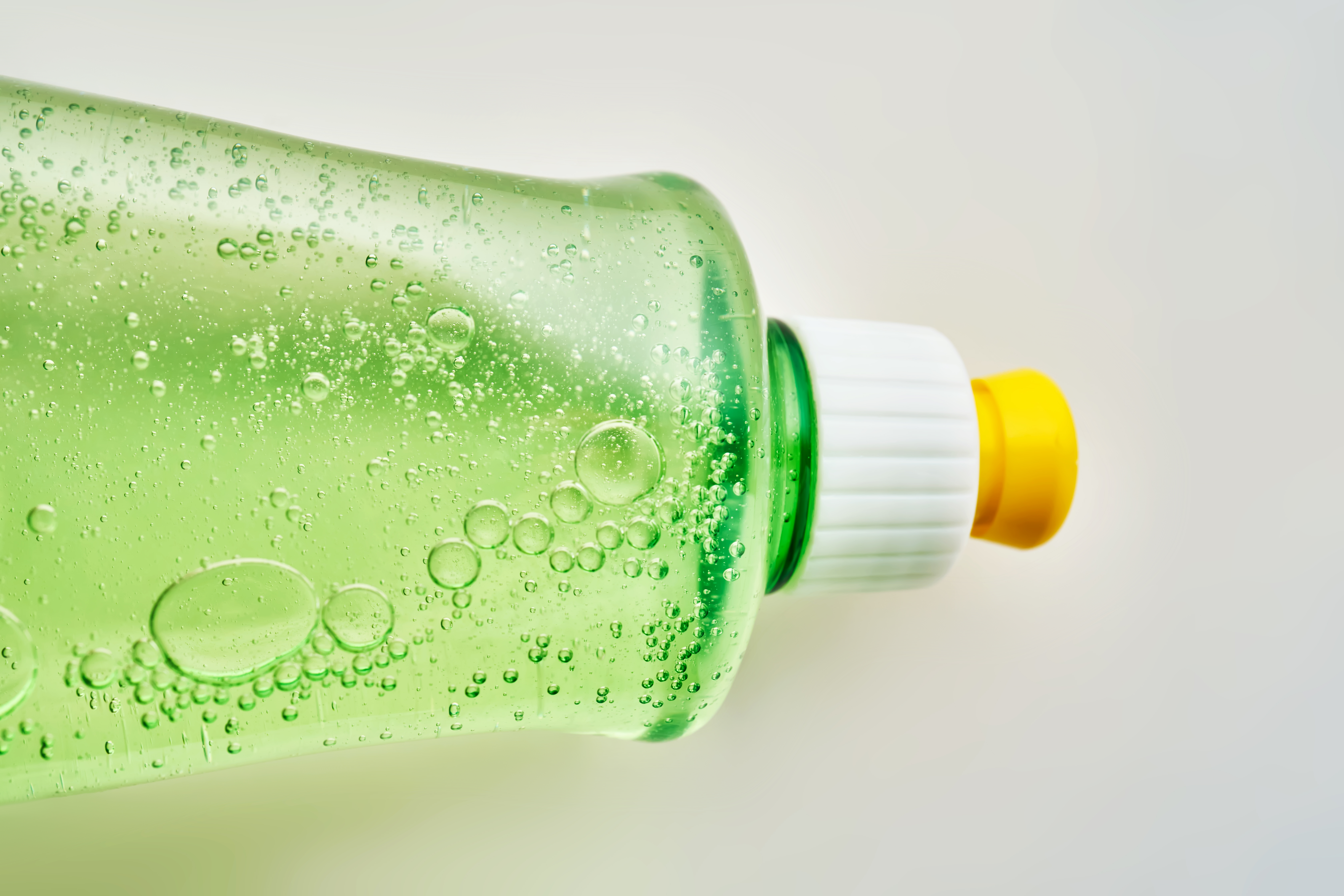 Green transparent bottle of dishwashing detergent with bubbles to get wine stains out