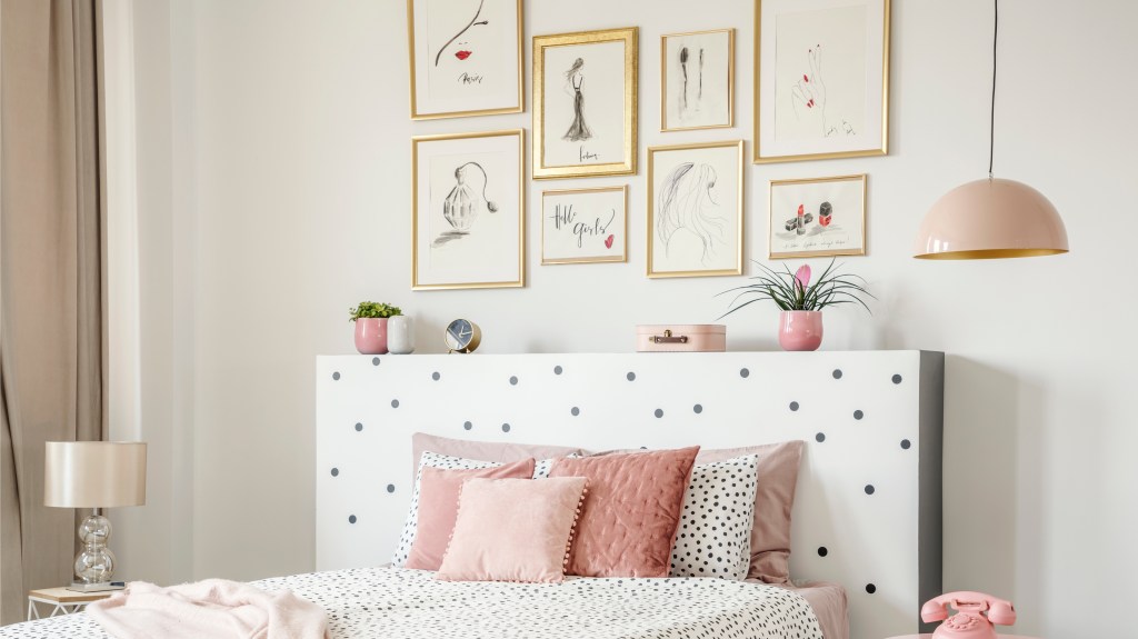 Gallery wall ideas brass framed fashion and beauty-themed prints grouped together on a wall above a bed