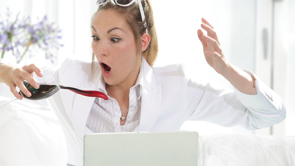 Woman dressed in white spilling glass of wine