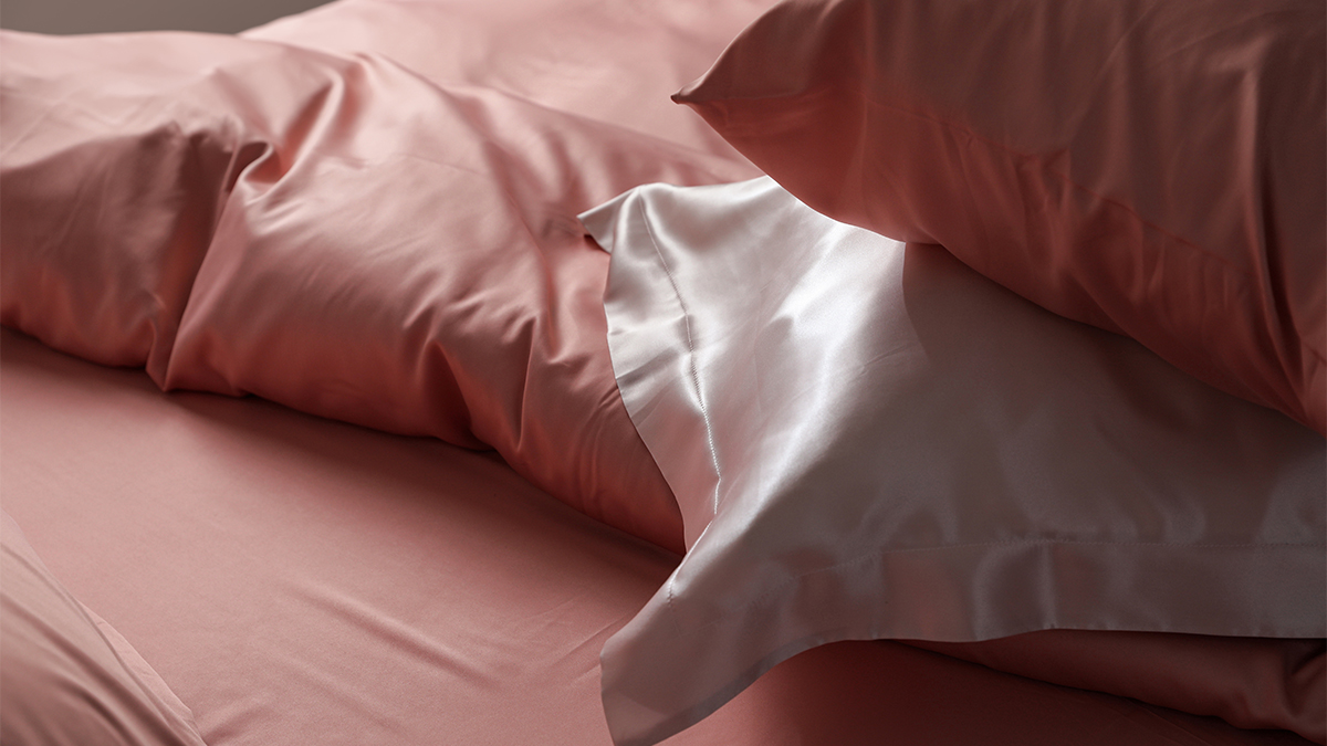 pink silk pillowcases on pillows on a bed