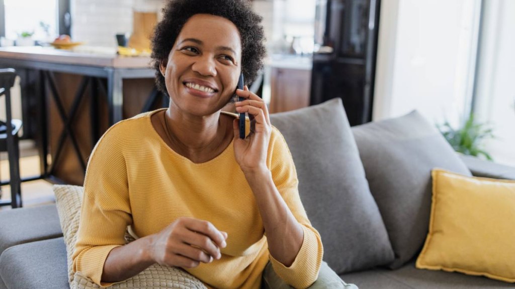AAA work from home: Portrait of mid adult woman sitting on the couch in the living room and talking on the phone