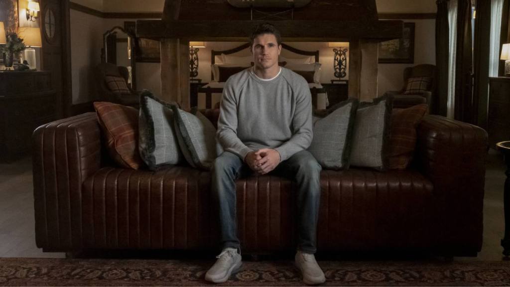 Robbie Amell sitting in a publicity still in “Upload”
