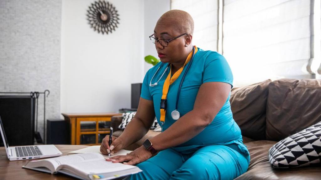 work from home nursing jobs:A black female nurse studying for another degree studies between her shifts