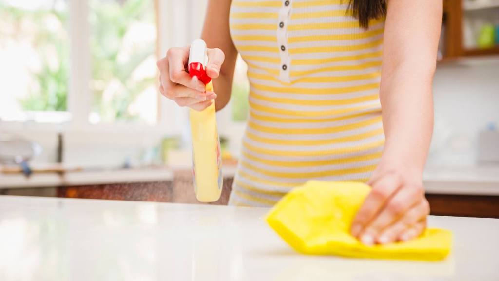 Cleaning Motivation: Hispanic woman spraying and wiping counter