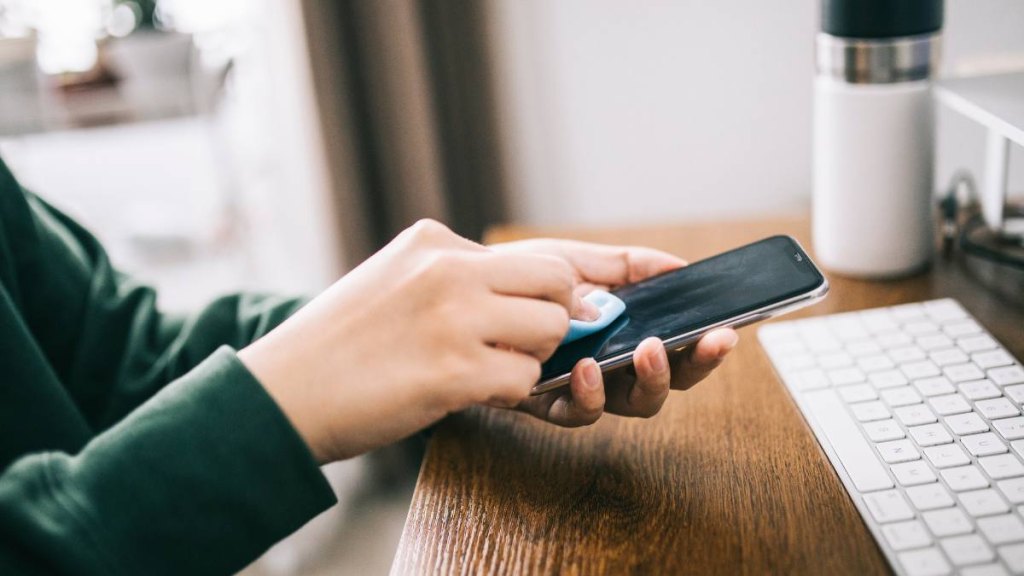 How to clean a TV screen: hands cleaning the surface of a smartphone