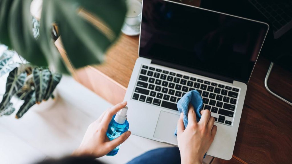 How to clean a TV screen: Cropped shot of a young woman cleaning the surface of laptop with cleaning spray and antistatic cloth at home