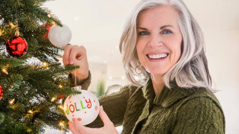 Christmas aesthetic: Portrait of Caucasian woman hanging ornaments on Christmas tree