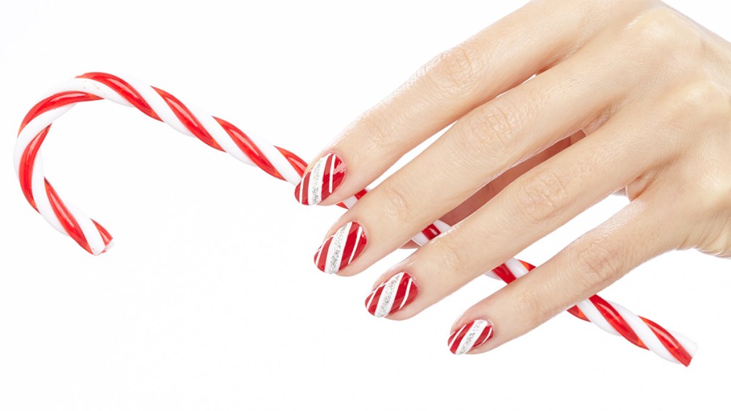 Nails painted with a candy cane stripe design, one of the holiday nail ideas
