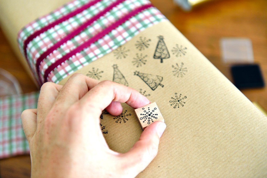 Holiday party: Hand stamping christmas prints on a Christmas gift wrapped in brown paper