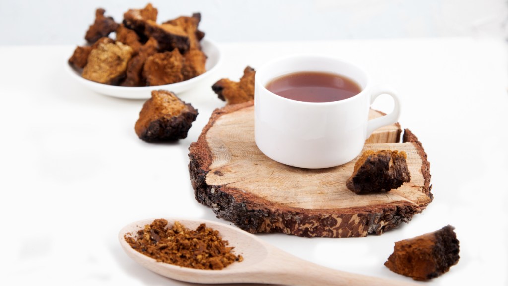 Chaga tea on a birch slice of wood beside ground chaga