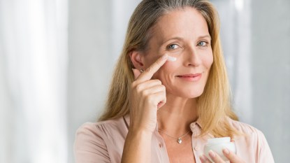 Woman applying anti aging probiotic-infused lotion on face for skin health