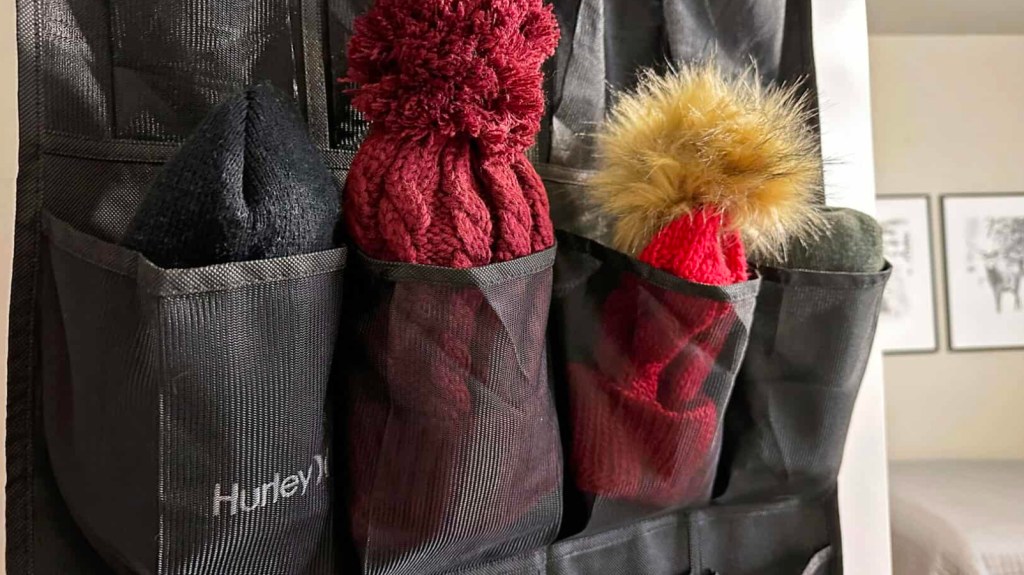 How to organize winter hats and gloves: Beanies stashed into the compartments of a black over-the-door shoe organizer