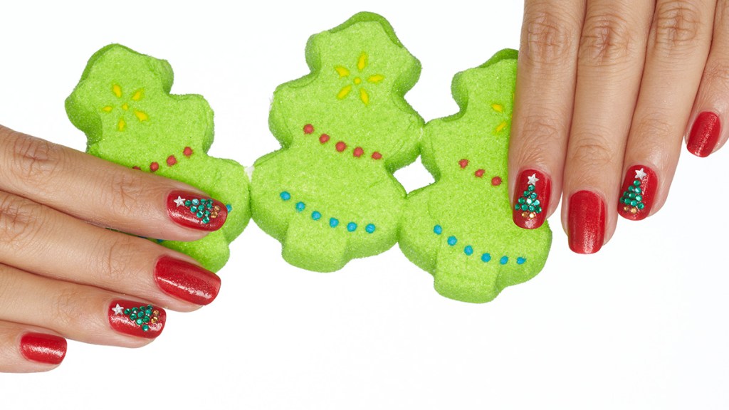 Nails painted with red polish and rhinestones in the shape of a Christmas tree, one holiday nail ideas