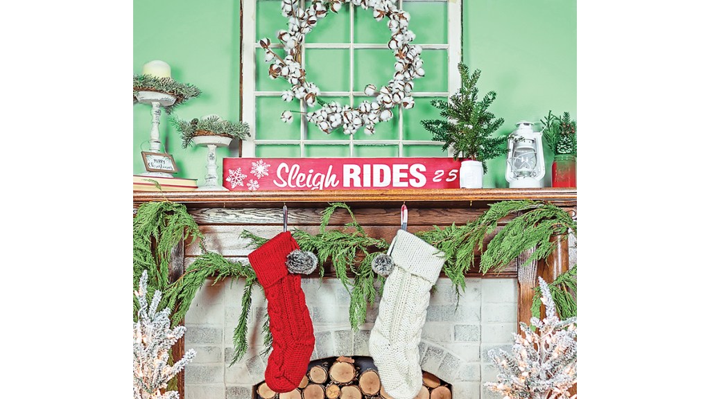 Christmas mantel ideas: Cozy cottage mantel featuring an old windowpane, cotton wreath, candlesticks, sleigh rides sign and fresh greenery garland on wood mantel