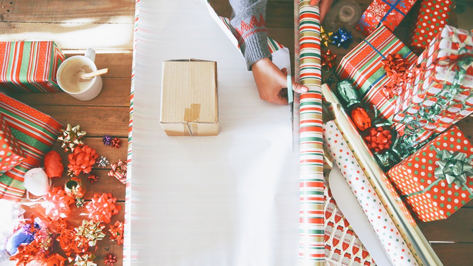 Gift wrap supplies and a woman cutting wrapping paper: How to wrap a gift