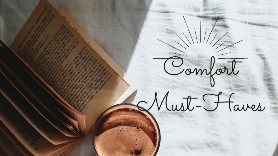 An image of a coffee mug and book laid open on soft sheets with text that reads 'Comfort Must-Haves.'