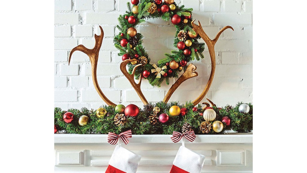 Christmas mantel ideas: Traditional Christmas mantel featuring a bauble-kissed garland and wreath and reindeer antlers on white mantel
