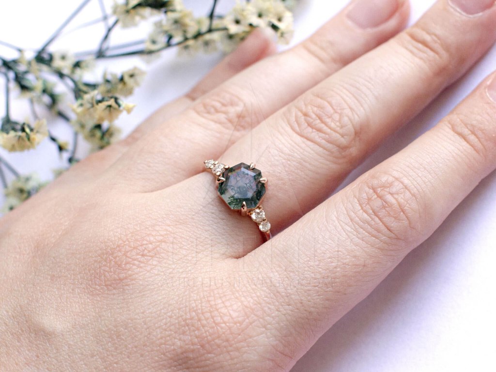 Next on the list is Heptagon Moss Agate and Diamond Ring which effortlessly combines an unusual geometric stone setting and classic side diamonds. 7-sided gemstones are not something you see often so one could say this is your lucky day!
Even though a baguette cut can be considered a hybrid between a classic and geometric stone cut, we felt the need to include it on the list. This Aurelius Baguette Moss Agate Engagement Ring is flanked by marquise diamonds resembling leaves for a beautiful nature-inspired look.