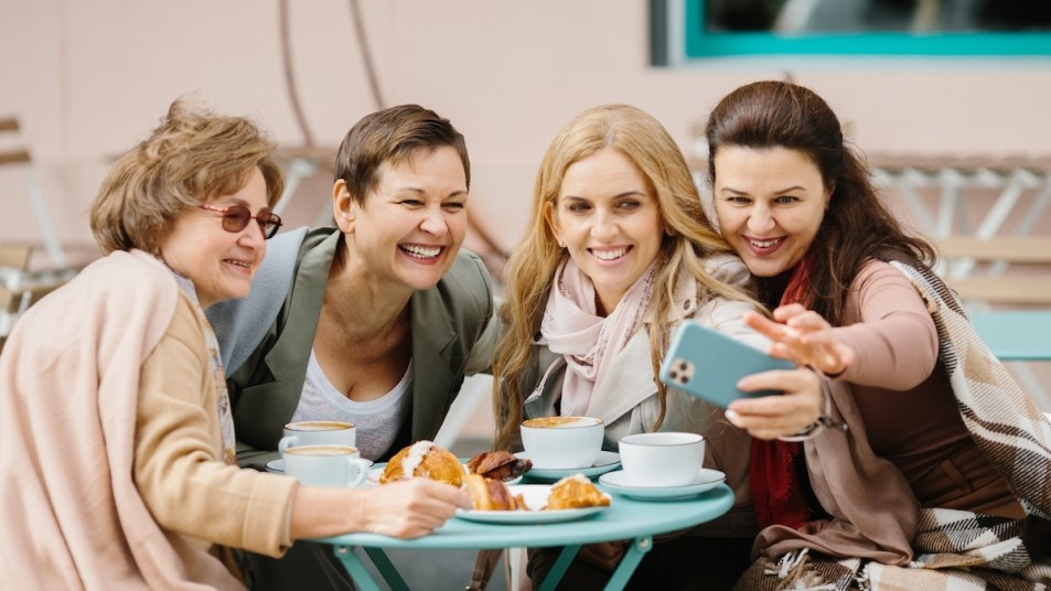 Four women taking a selfie at outdoor cafe