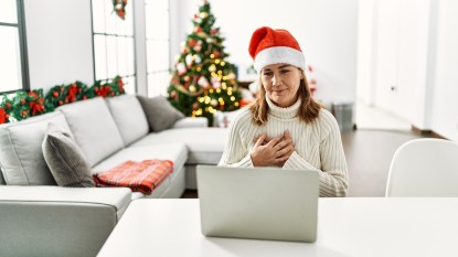 Woman wearing Santa hat and looking at computer with peaceful expression