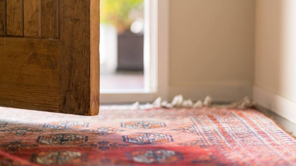 How to flatten a rug: Low angle view looking out an opening domestic front door