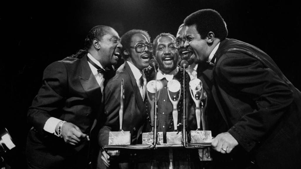 The Temptations speaking into a microphone